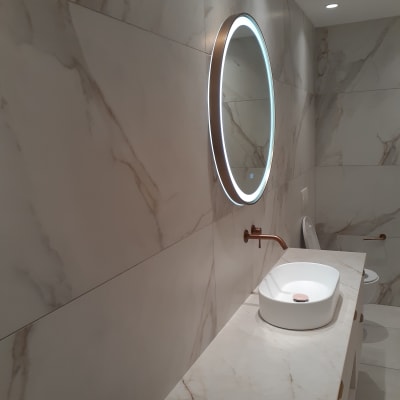 כיור לבן עם ברז נחושת במקלחת מודרנית