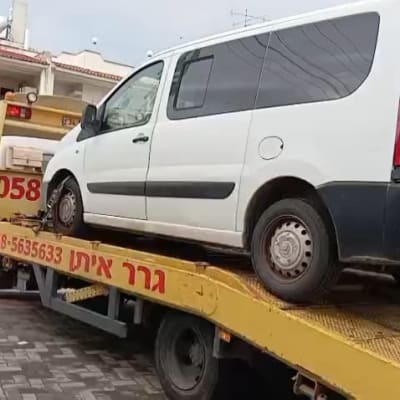 רכב לבן על גרר צהוב בשירותי דרך