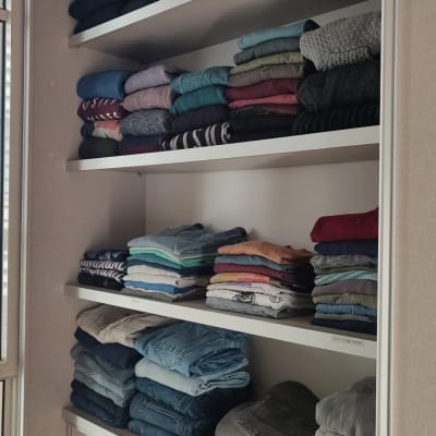 בגדים מקופלים מסודרים על מדפים בארון פתוח