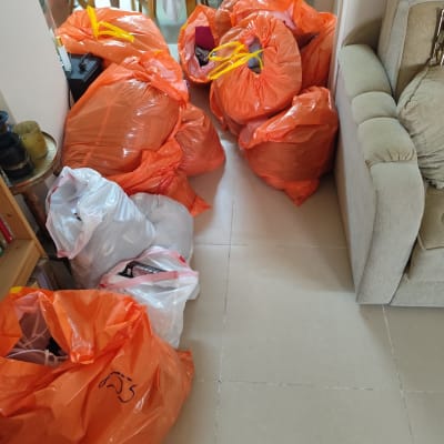 שקיות כתומות ולבנות מלאות בחפצים על רצפת חדר