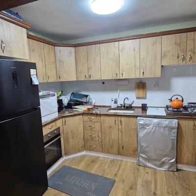 מטבח עם ארונות עץ, מקרר שחור, קומקום כתום