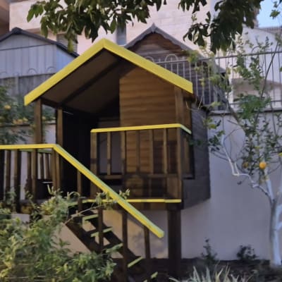 בית עץ קטן עם גג צהוב בגינה