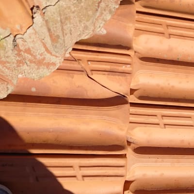 רעפים שבורים על גג עם צל של נעל