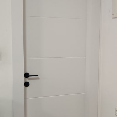 דלת לבנה עם ידית שחורה על רקע קיר לבן