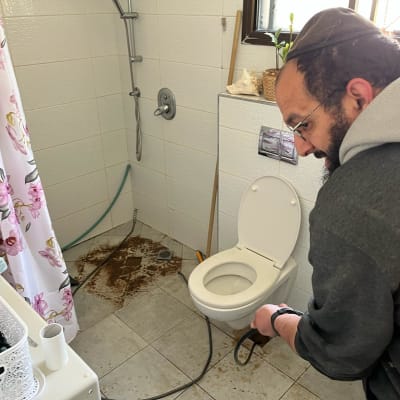 אדם עובד על שירותים עם כלי עבודה