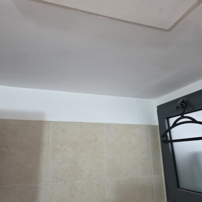 תקרה וקיר צבועים בלבן עם חלון בצד