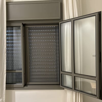 תריסים אפורים סגורים ליד חלון פתוח