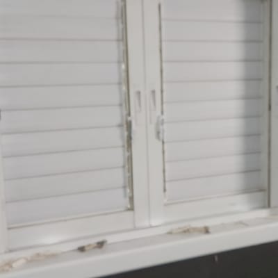 תריסים לבנים מותקנים על חלון קיר כהה