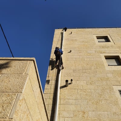 אדם מטפס על קיר בניין לצורך עבודת איטום