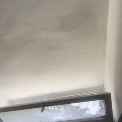 חלון קטן עם מסגרת מתכת וקיר צבוע לבן