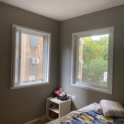 חדר עם חלונות פתוחים, מיטה וארון קטן