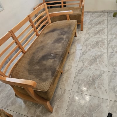 ספה עם כתמים כהים על הריפוד, צינור שואב אבק על הרצפה