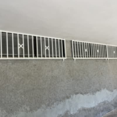 סורגים לבנים על חלונות קטנים בקיר בטון אפור