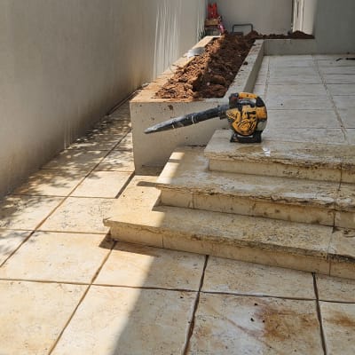 מכשיר עבודה על מדרגות אבן ליד ערוגת אדמה