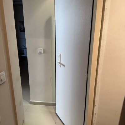 דלת פתוחה עם ידית לבנה על קיר בהיר