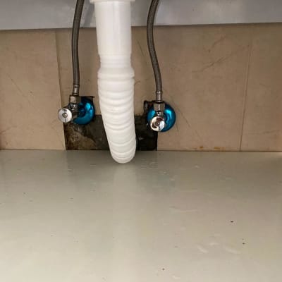 צינור ניקוז לבן וברזים כחולים מתחת לכיור