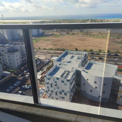 נוף עירוני מבעד לחלון זכוכית עם מסגרת מתכת