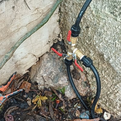 ברזים וצינורות ליד קיר אבן עם עלים יבשים