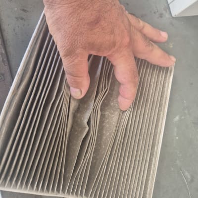 יד מחזיקה מסנן אוויר מלוכלך על שולחן עבודה