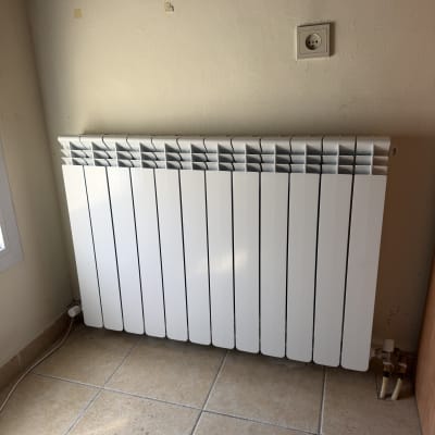 רדיאטור חימום לבן מותקן על קיר כחלק ממערכת הסקה ביתית