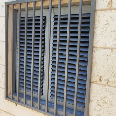 חלון עם תריסים וסורגים על קיר אבן