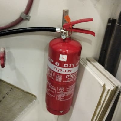 מטף כיבוי אש מותקן על קיר עם צינור