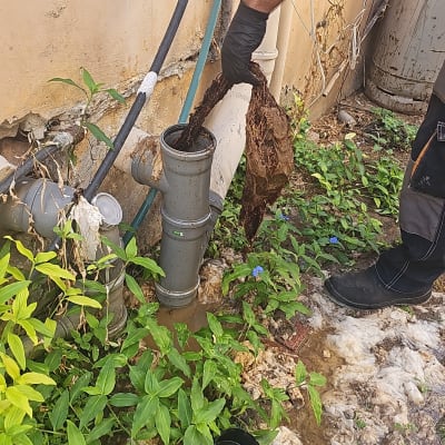 אדם עם כפפה מוציא פסולת מצינור ביוב