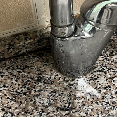 ברז מים על משטח שיש עם סימני רטיבות