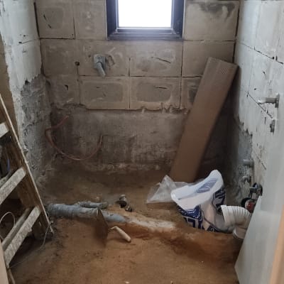 חדר בשיפוץ עם קירות חשופים וכלי עבודה על הרצפה