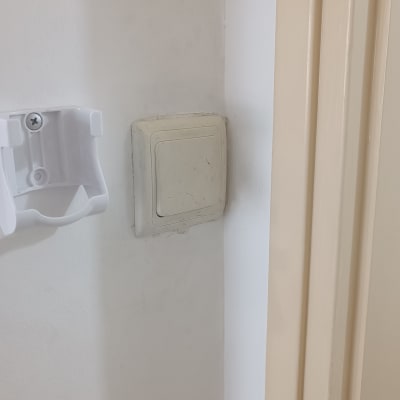 מתג חשמל על קיר לבן ליד מתקן פלסטיק