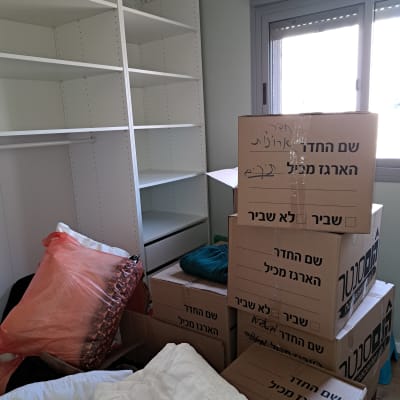 ארגזים מסומנים ליד מדפים ריקים בחדר