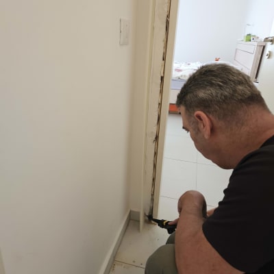 מדביר משתמש בכלי ריסוס ליד דלת