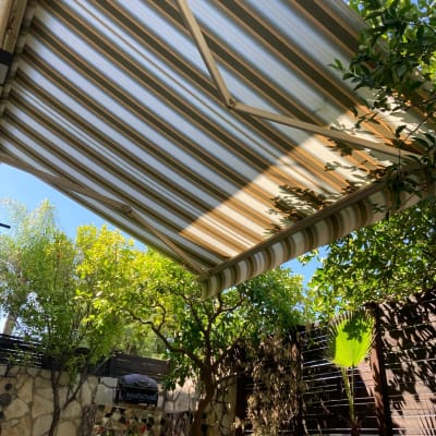 סוכך פסים צבעוני בגינה עם עצים מסביב