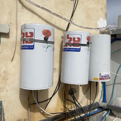 דודי שמש מותקנים על קיר עם צינורות חשמל ומים