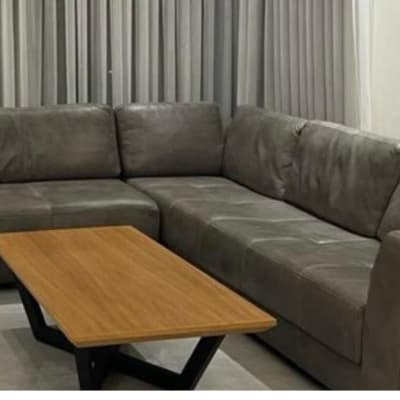 ספה אפורה ושולחן עץ בסלון עם וילונות אפורים