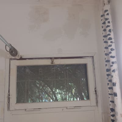 קיר עם סימני צבע ליד חלון קטן