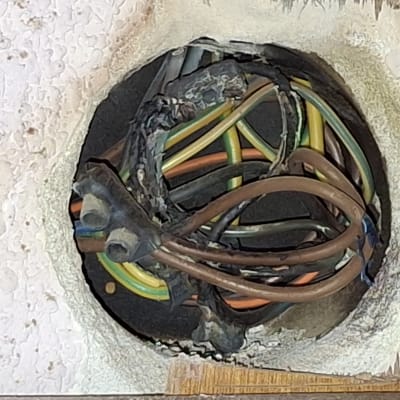 חוטי חשמל צבעוניים בתוך קיר עם בידוד פגום