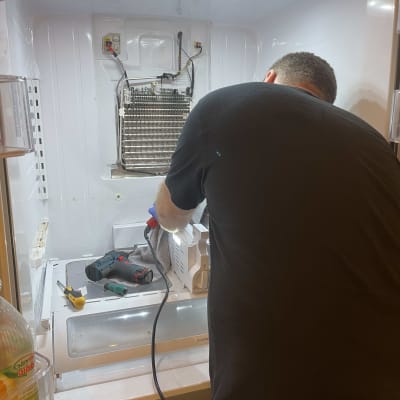 אדם מתקן מקרר עם כלים חשמליים בפנים