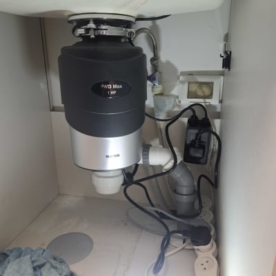 מתקן טוחן אשפה מתחת לכיור עם חיבורים וצינורות