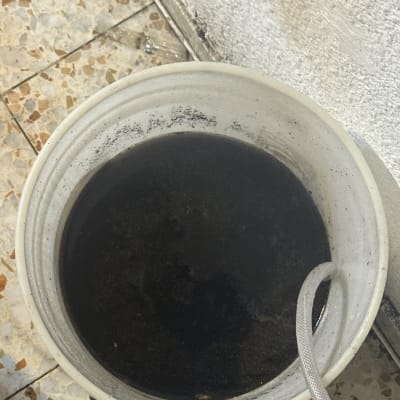 דלי עם מים כהים וצינור, כנראה קשור למיזוג אוויר