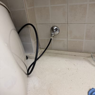 צינור שחור מחובר לשסתום על קיר אריחים