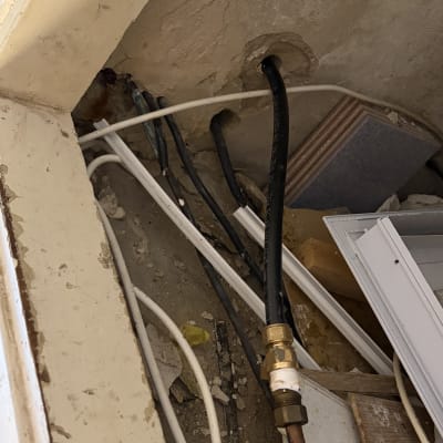חיבור צנרת ומחבר פליז בקיר במהלך עבודות אינסטלציה לדוד