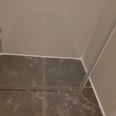 רצפת מקלחת עם אריחים כהים ודלת זכוכית