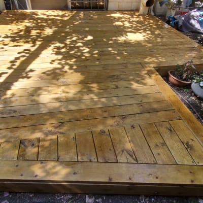 דק עץ בגינה עם עציצים מסביב