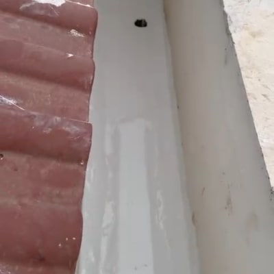 גג אטום עם חומר איטום לבן ליד רעפים אדומים