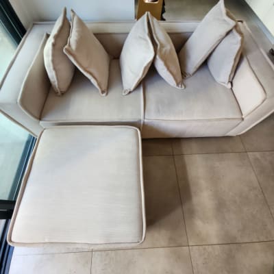 ספה בהירה עם כריות על רצפת אריחים