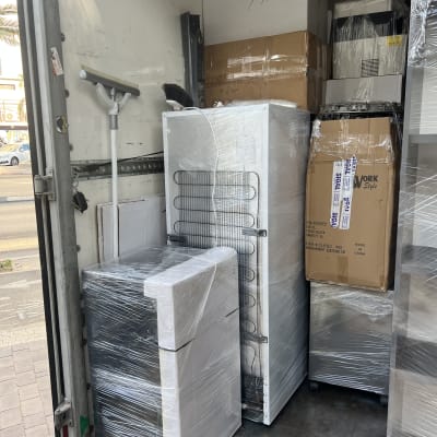 מכשירי חשמל וארגזים עטופים בניילון בתוך משאית הובלה