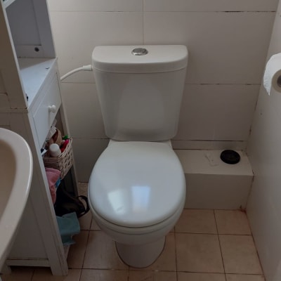 אסלה לבנה עם מיכל הדחה בחדר אמבטיה