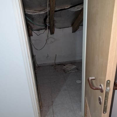 חדר קטן עם תקרה פתוחה וחוטי חשמל גלויים