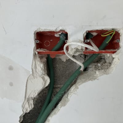 קופסאות חשמל פתוחות עם צינורות ירוקים בקיר